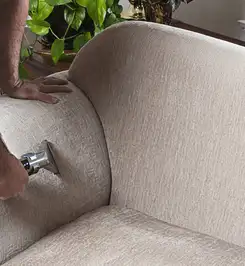 Professional upholstery cleaner deep-cleaning a fabric sofa with a handheld extraction tool and hose Tucson, AZ.